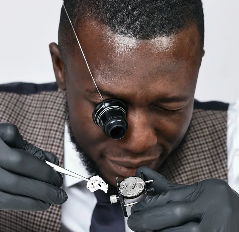 Watchmaker with loupe assembling a mechanical movement